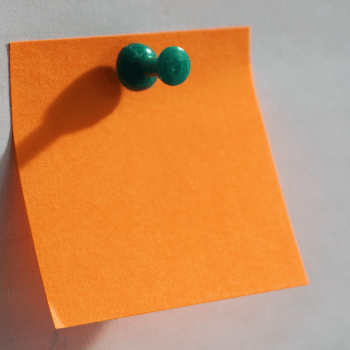 blank orange post it note with a green pin in it