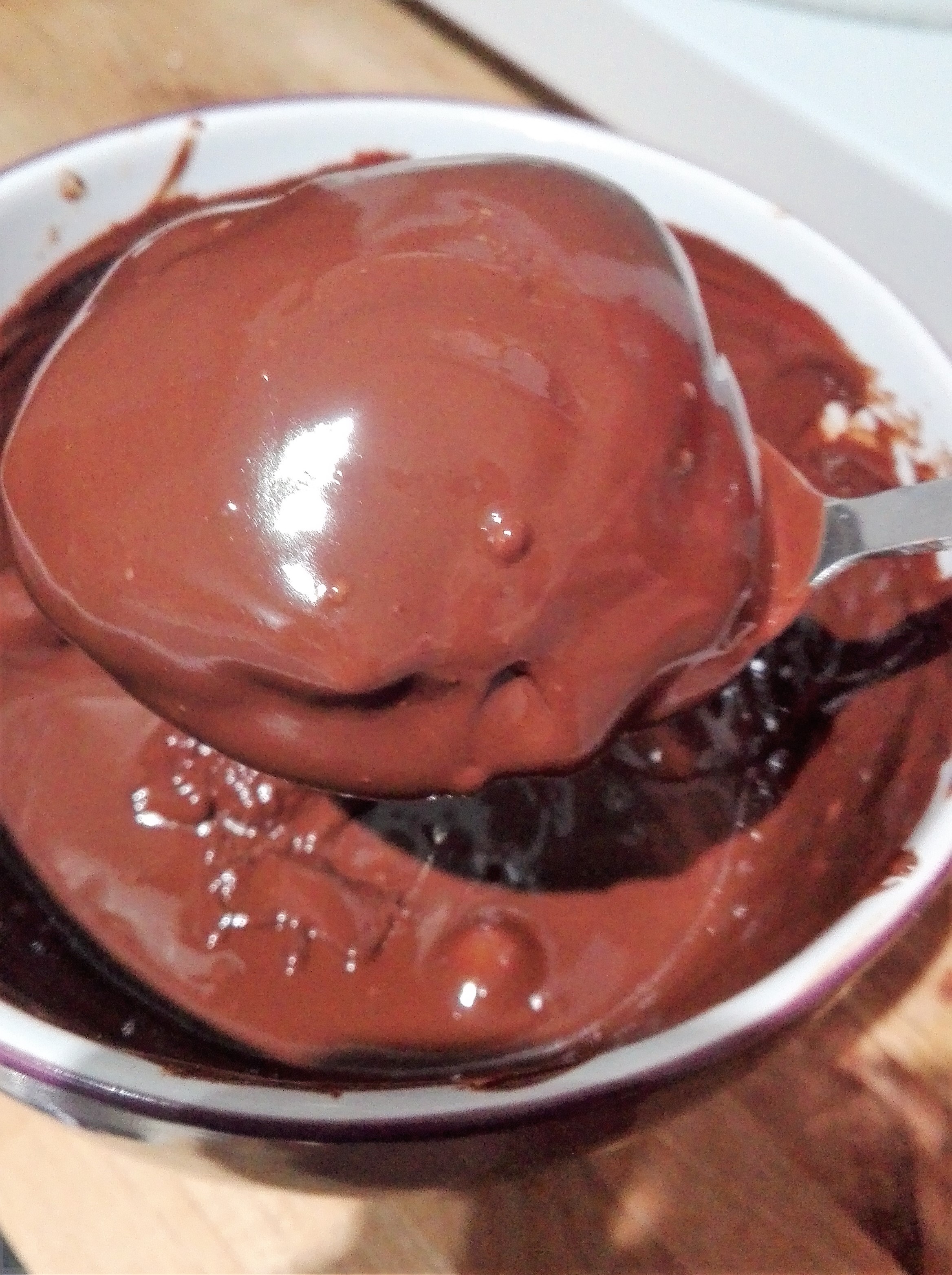 gluten free lebkuchen being dunked in a bowl of melted chocolate with a spoon