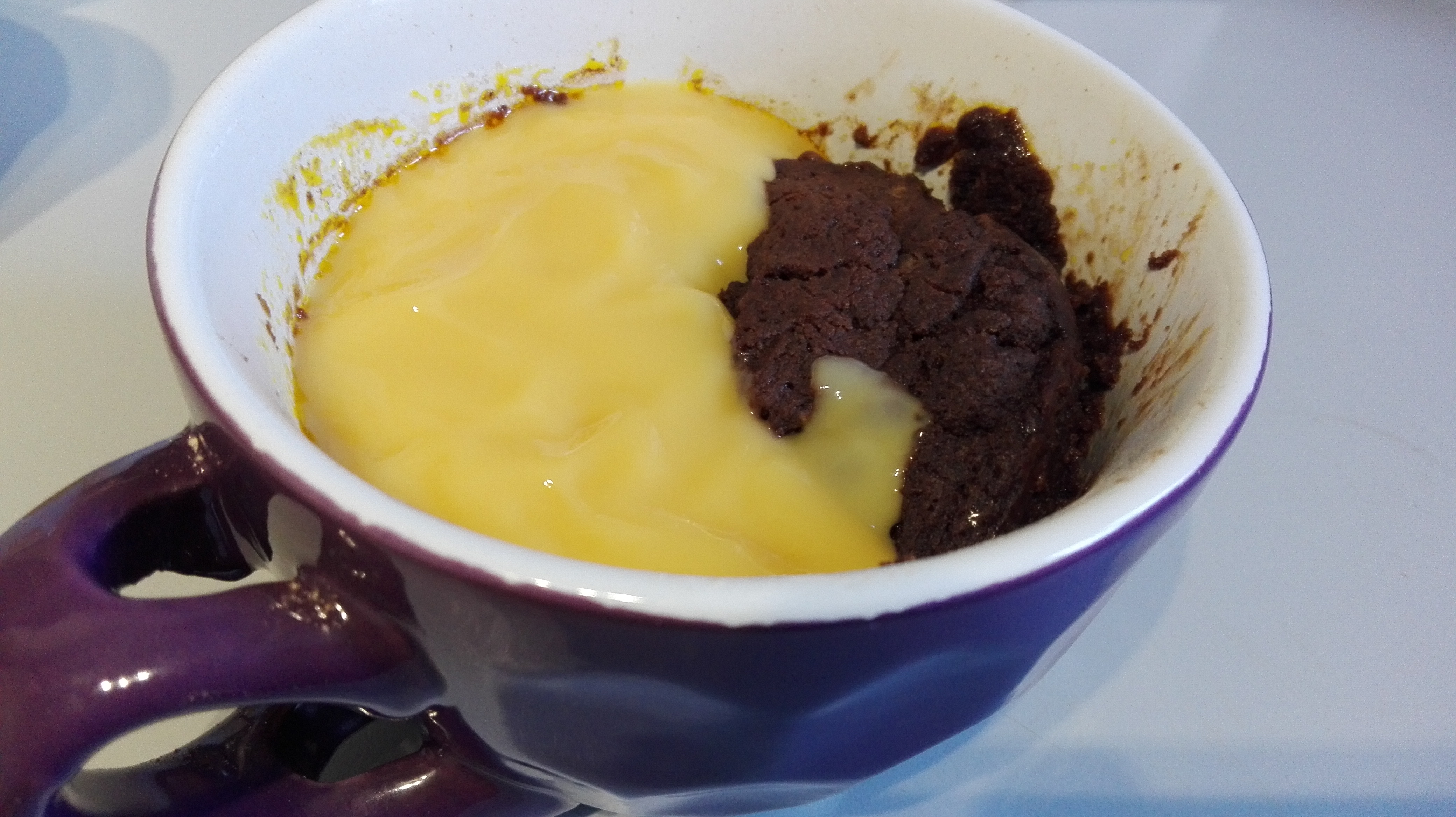 purple mug on kitchen worktop containing chocolate mug pudding and custard