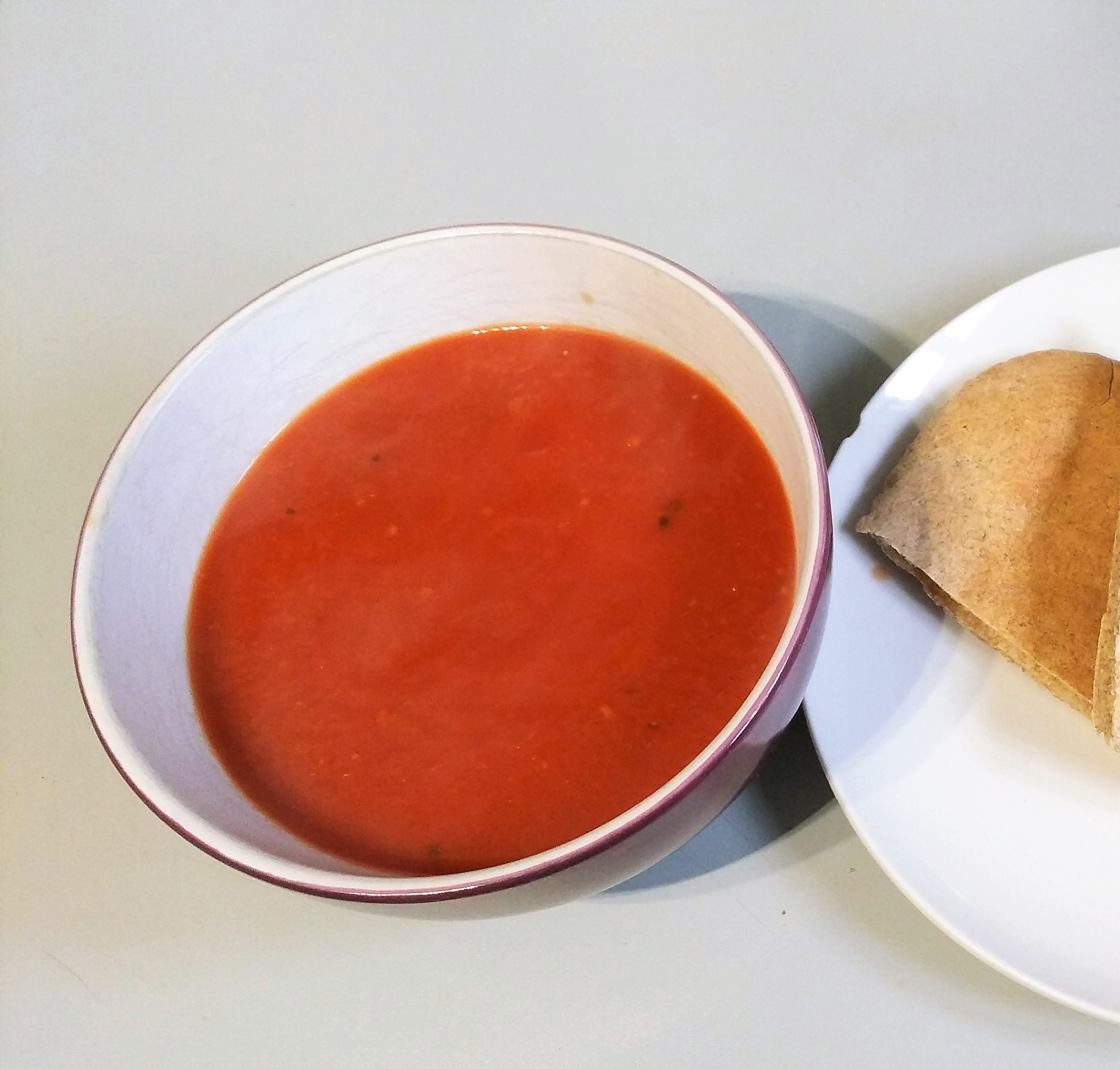 Bowl of tomato, orange and ginger soup on a kitchen counter. Easy vegan dinner recipes