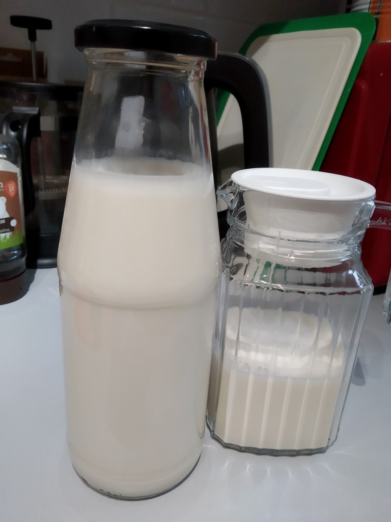 homemade dairy free oat milk in a glass bottle and glass jug. Recycling glass bottles is great for sustainability.
