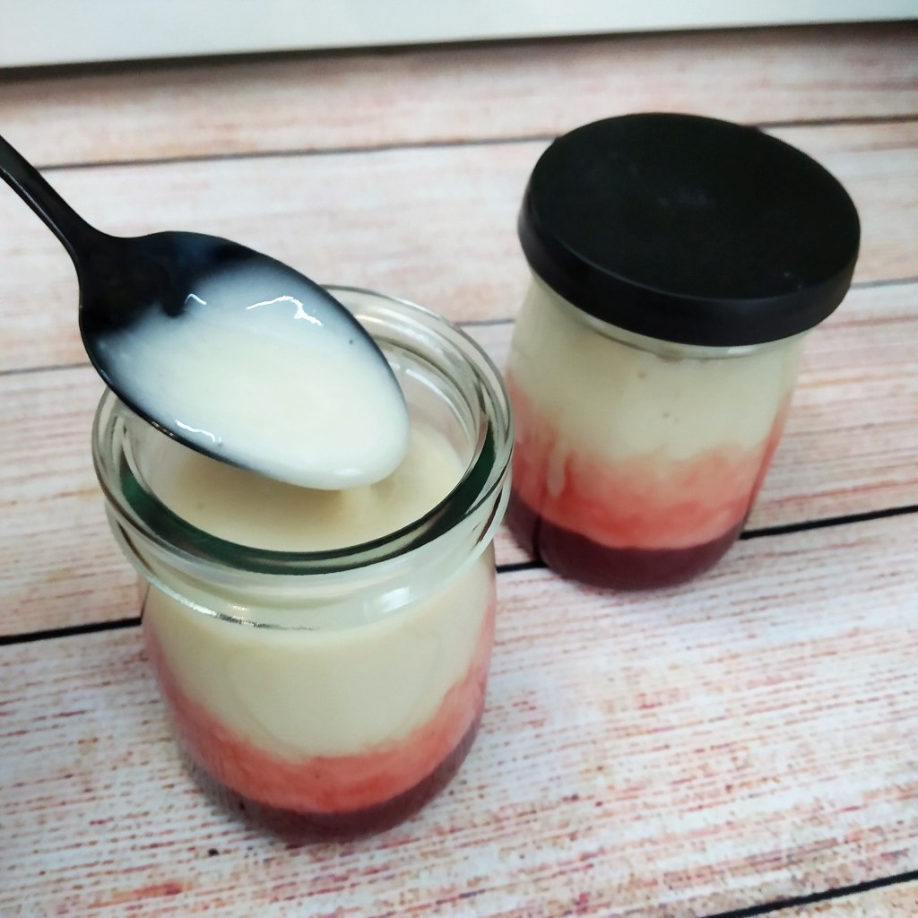 dairy free soy yoghurt with strawberry sauce in a jar with a spoon