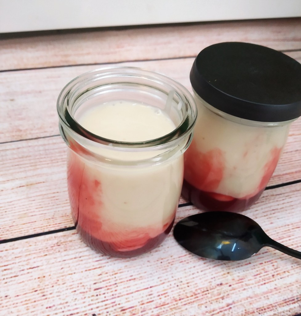 dairy free vegan yoghurt with strawberry in jars on a table with a spoon