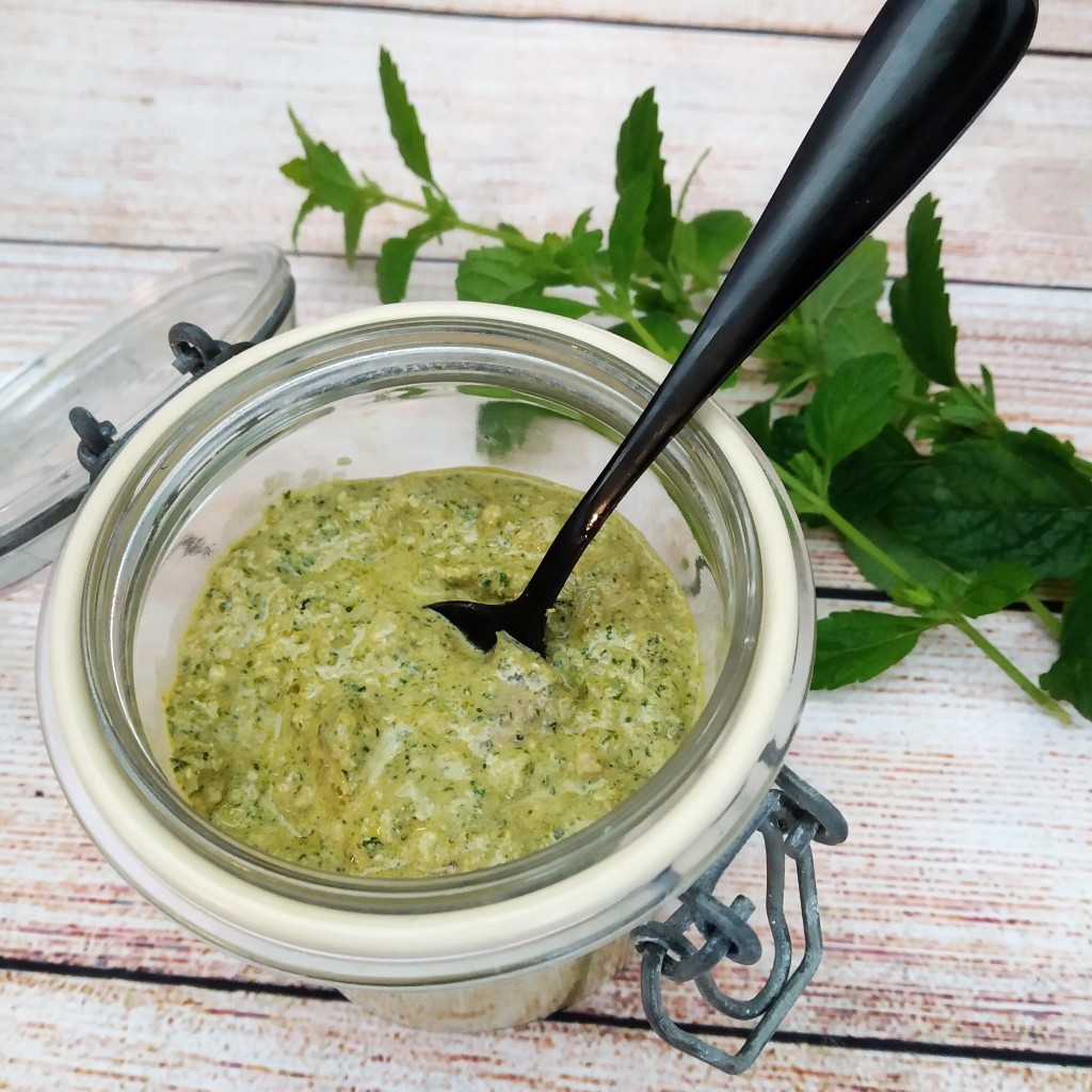 vegan soy free lemon balm pesto recipe in a glass jar with a spoon on a table