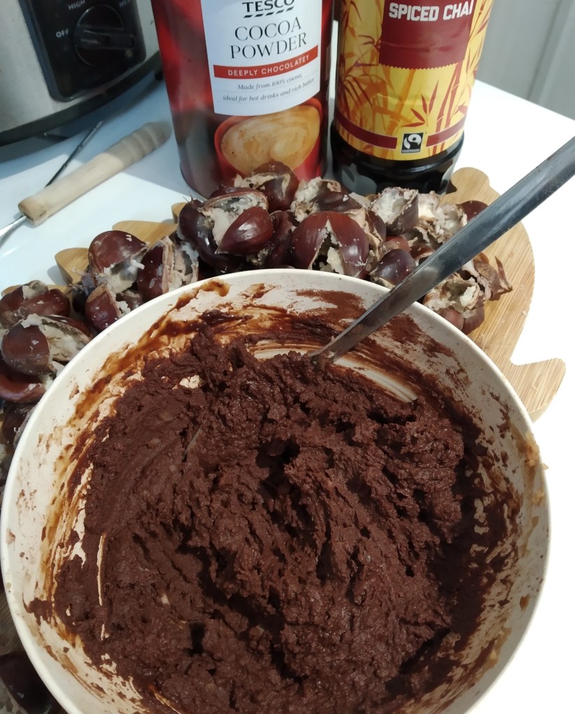 allergy friendly chocolate spread recipe using foraged chestnuts in a bowl on a kitchen worktop. In the background there is a tub of cocoa powder and a bottle of syrup