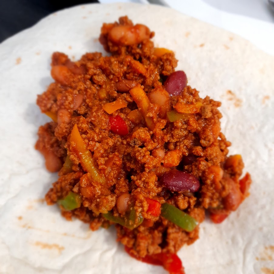 easy vegan burrito recipe. Filling on an open tortilla waiting for cheese
