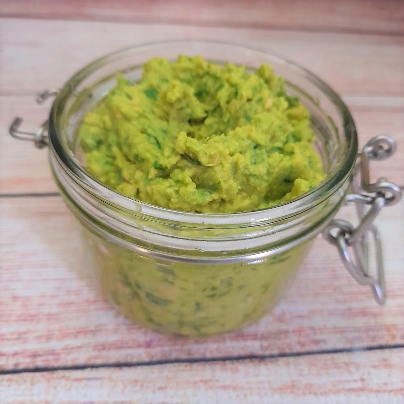wild garlic hummus recipe without tahini, vegan, in a glass jar on a table.